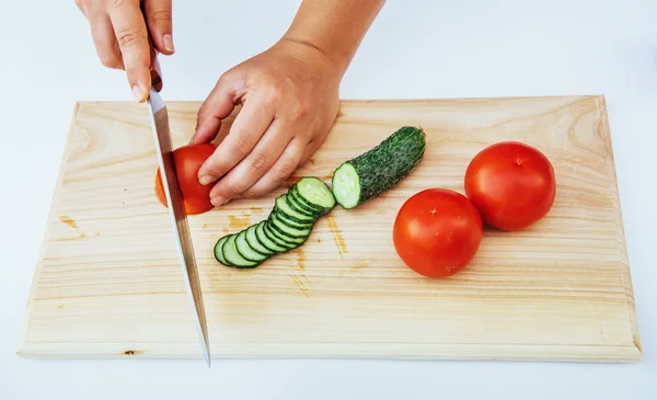 Houten plank met een mes en tomaat en komkommer — Stockfoto
