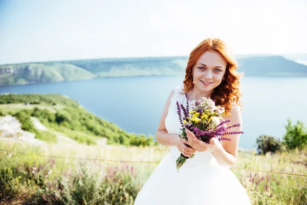 Noiva com um buquê de flores perto da água — Fotografia de Stock