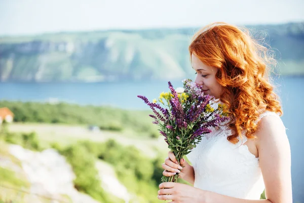 Bruid met een boeket van bloemen in de buurt van het water — Stockfoto