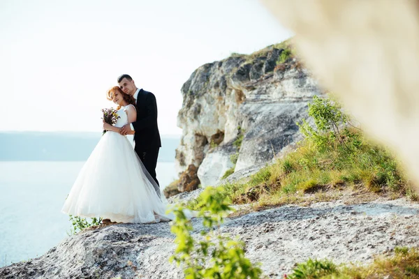 Hermosa novia rubia y novio con clase en las rocas, en medio de la se — Foto de Stock