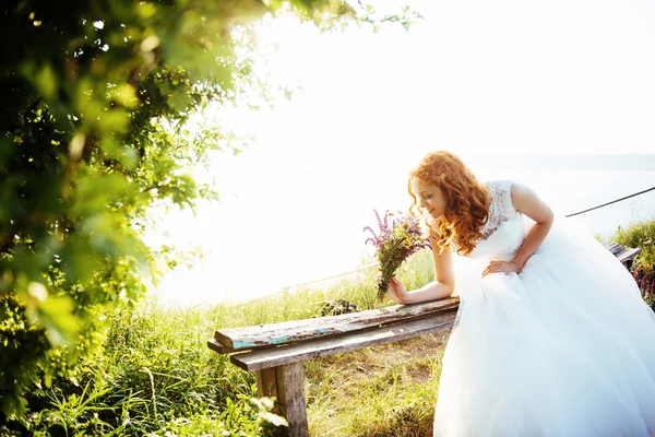 Sposa con un mazzo di fiori vicino all'acqua — Foto Stock