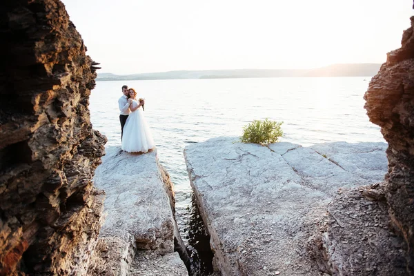 Πανέμορφη ξανθιά νύφη και κομψό γαμπρό σε βράχια, σε t — Φωτογραφία Αρχείου