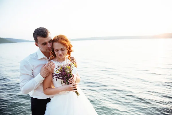Gorgeous blonde bride and groom classy on the rocks, amid the se — Stock Photo, Image