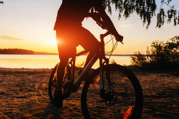 Menino em uma bicicleta ao pôr do sol — Fotografia de Stock