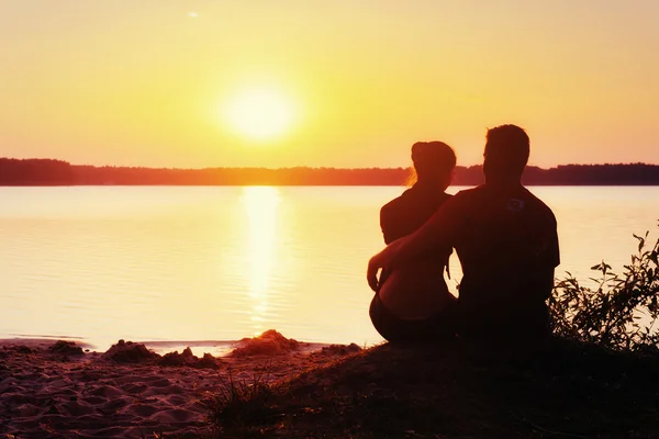 Casal romântico na praia ao pôr do sol colorido no fundo — Fotografia de Stock