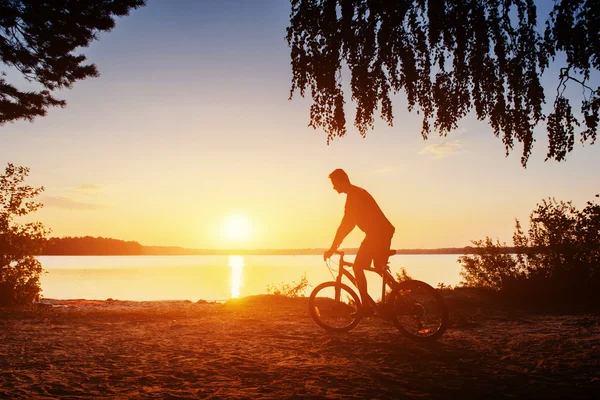 Jongen op een fiets bij zonsondergang — Stockfoto