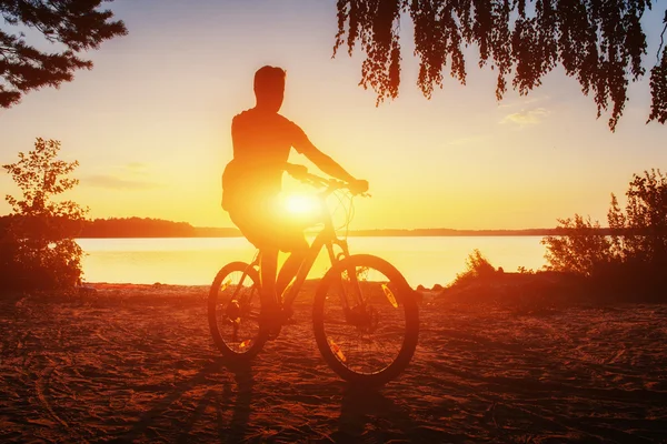 Jongen op een fiets bij zonsondergang — Stockfoto