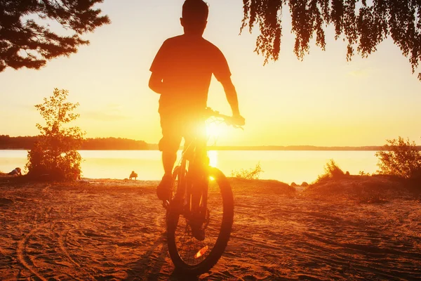 Menino em uma bicicleta ao pôr do sol — Fotografia de Stock