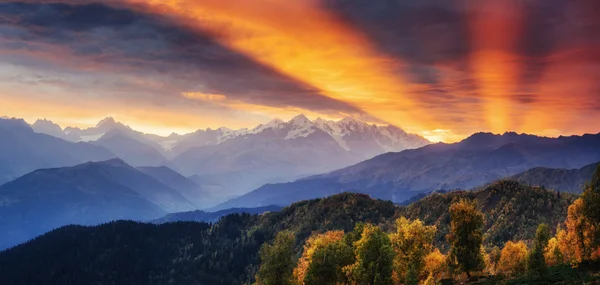 Sunset over snow-capped mountain peaks. The view from the mounta — ストック写真