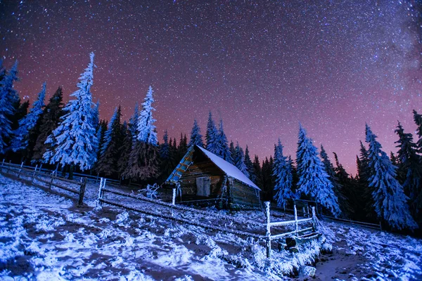 Cabaña en las montañas. Fantástica lluvia de meteoritos de invierno y nieve m — Foto de Stock