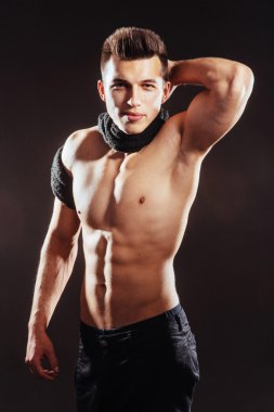Karanlık bir arka plan üzerinde çıplak bir gövde ile seksi genç adam 