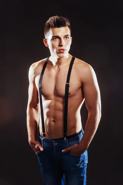 Portrait of a man with nude torso fitness standing in jeans with — Stock Photo, Image