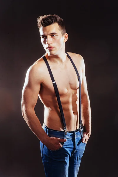 Portrait of a man with nude torso fitness standing in jeans with — Stock Photo, Image