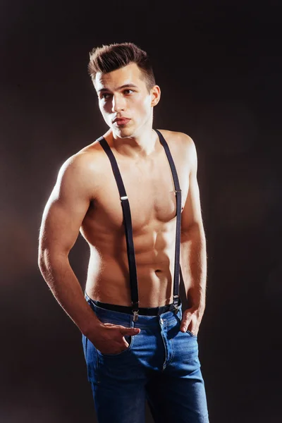 Portrait of a man with nude torso fitness standing in jeans with — Stock Photo, Image