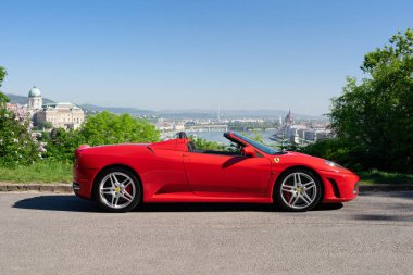 BUDAPEST, HUNGARY - 11 Mayıs 2021: Ferrari F430 - Pininfarina tarafından tasarlanan Örümcek, İtalyan spor otomobili, Budapeşte panoraması ile Gellert Hill gözleme noktası tarafından fotoğraflandı.
