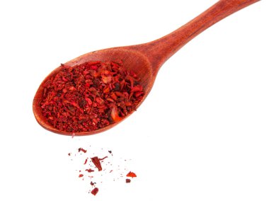 Beyaz arka planda izole edilmiş ahşap kaşıkta kurutulmuş domates ve kırmızı biber.