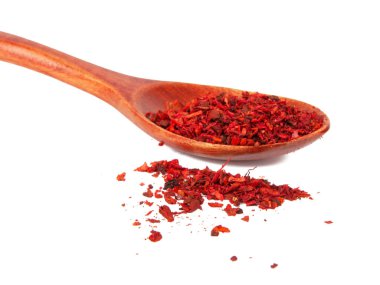 Beyaz arka planda izole edilmiş ahşap kaşıkta kurutulmuş domates ve kırmızı biber.