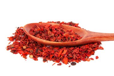 Beyaz arka planda izole edilmiş ahşap kaşıkta kurutulmuş domates ve kırmızı biber.