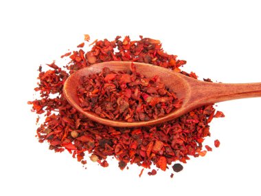 Beyaz arka planda izole edilmiş ahşap kaşıkta kurutulmuş domates ve kırmızı biber.