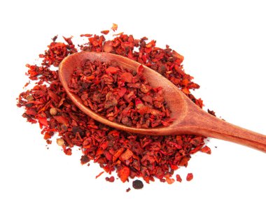 Beyaz arka planda izole edilmiş ahşap kaşıkta kurutulmuş domates ve kırmızı biber.