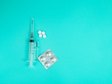 Yeşil arka planda şırınga, ampul ve beyaz haplar