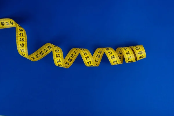 Yellow tape measure on the blue background