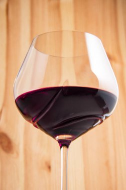 Kaliteli ahşap arka planda kırmızı şarap kadehi.