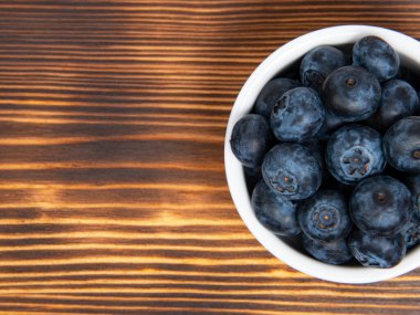 Ahşap zemin üzerinde beyaz tabakta taze yaban mersini.