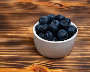 Ahşap zemin üzerinde beyaz tabakta taze yaban mersini.