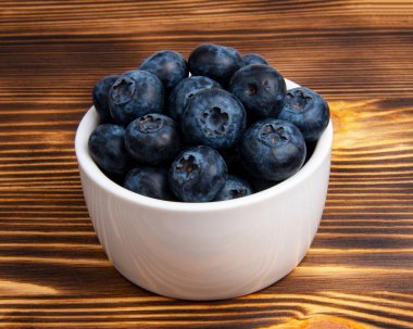 Ahşap zemin üzerinde beyaz tabakta taze yaban mersini.