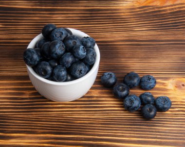 Ahşap zemin üzerinde beyaz tabakta taze yaban mersini.