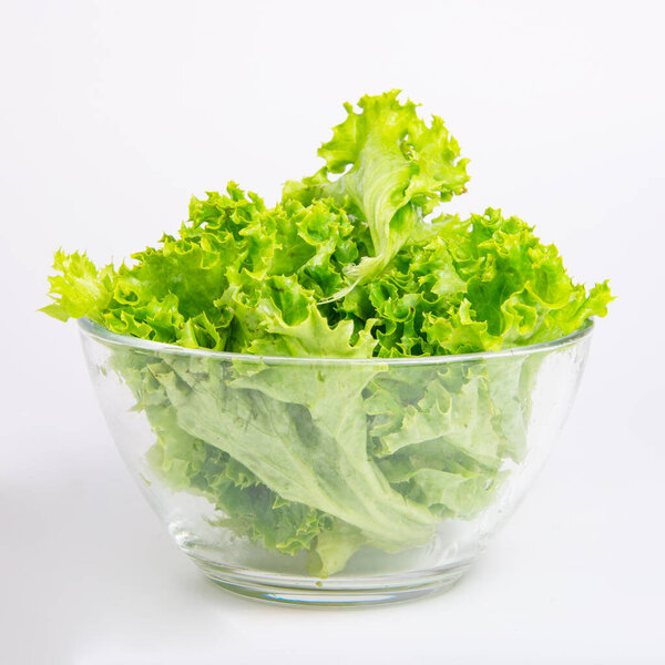 Green fresh salad of lettuce in glass dish on the white background