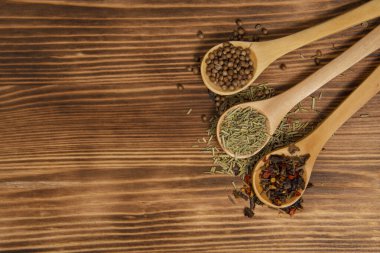 Doğal ahşap arka planda farklı kuru baharatlı üç tahta kaşık.