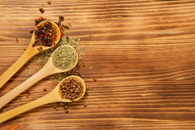 Doğal ahşap arka planda farklı kuru baharatlı üç tahta kaşık.