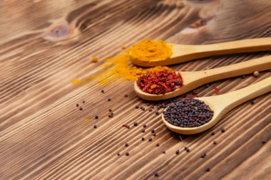 Aroma ahşap kaşık ve doğal ahşap arka planda farklı kuru baharatlar.