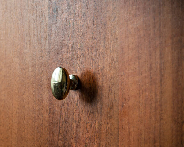 Door metalic knob on brown wooden background