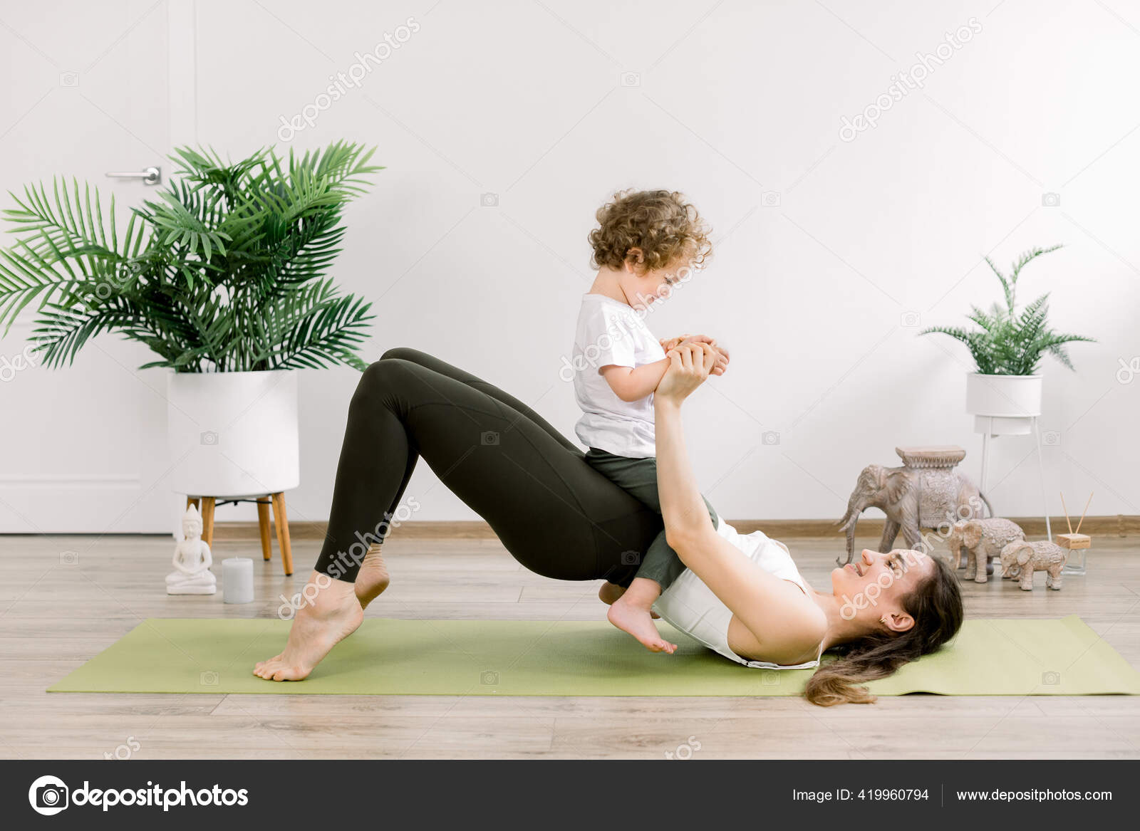 Young happy sporty woman mother working out, doing butt bridge pilates yoga  exercise, little kid son on her belly. Healthy lifestyle, fitness,  postnatal yoga, maternity concept Stock Photo by ©sofiiashunkina@gmail.com  419960794