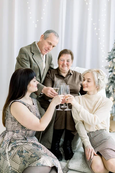 Celebration, family, generations and holidays concept. Senior happy couple clinking champagne glasses with their young pretty two granddaughters, celebrating New Year or Christmas — Stock Photo, Image