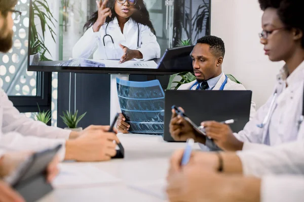 Kendine güvenen çok ırklı doktorlardan oluşan bir ekip modern hastane odasında video konferansı yapıyor. Bir grup profesyonel doktor tıbbi video danışmanlığında hastalar hakkında konuşuyor. — Stok fotoğraf