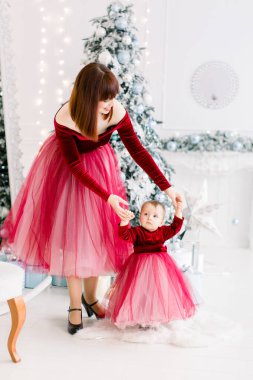 Sevimli, küçük, güzel bir kızın ilk adımları, neşeli, zarif bir annesi, onu destekleyen, kış tatillerini hafif Noel odasında geçirirken eğlenen.