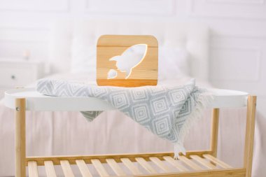 Evdeki ahşap tur ve dekorasyon ayrıntıları. Havalı ahşap el yapımı lamba, roketle kesilmiş resim, küçük sehpa üzerinde, açık ev yatak odasında duruyor.