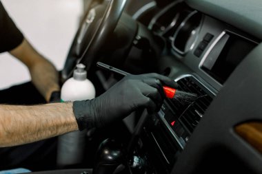 Araba bakımı, araba bakım konsepti. Siyah koruyucu eldivenli genç erkek işçinin el yapımı görüntüsü, yumuşak fırçalı araba paneli ve özel antistatik plastik sütle temizlenmiş.