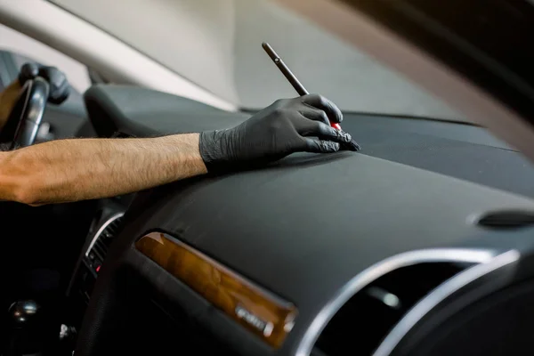 Car detailing and car wash concept. Cropped horizontal image of hand of car wash worker, cleaning gaps in the interior of the modern vehicle control panel, using the brush — Stock Photo, Image
