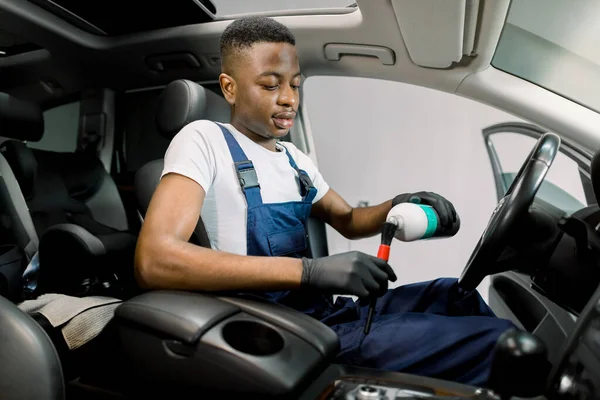 현대 자동차 안에 앉아서 부드러운 솔에 플라스틱 가공 우유를 붓고 있는 젊은 아프리카 남자 자동차의 모습. 자동차 디테일, 플라스틱 관리 — 스톡 사진