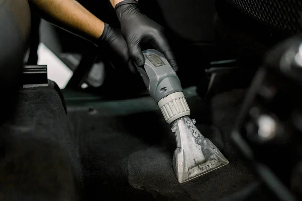 Cropped close up shot of hands of African male worker at auto service station, using vacuum cleaner in car, remowing the dust and sand. Vacuum cleaning inside the car — Fotografia de Stock