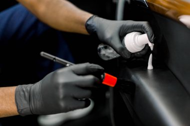 Afrika erkek araba temizleme atölyesinin yakın çekim görüntüleri, koruyucu eldivenler, yumuşak fırça tutmak ve araç kapısının yüzeyine temizleyici köpük sürme