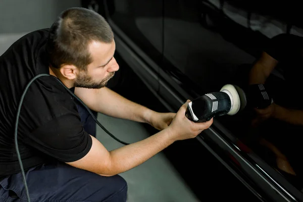 Car service worker polishing modern vehicle body with special wax from scratches and orbital polisher, close-up top view. Professional car detailing and maintenance concept — Stock Photo, Image