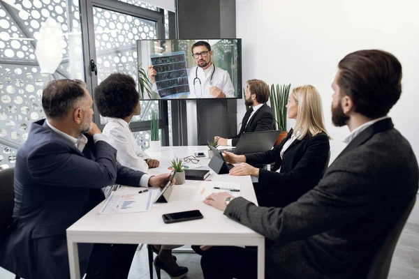 Videoconferência online, distanciamento social, reunião de webinar. Equipe de empresários multiétnicos, especialistas em saúde, em videoconferência com o jovem médico caucasiano experiente, realizando tomografia computadorizada — Fotografia de Stock