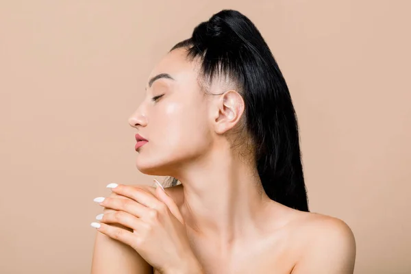 Perfil close up retrato de beleza de lindo agradável nua jovem mulher asiática com pele impecável, tocando seu ombro com prazer e olhos fechados. Fundo bege isolado e espaço de cópia — Fotografia de Stock