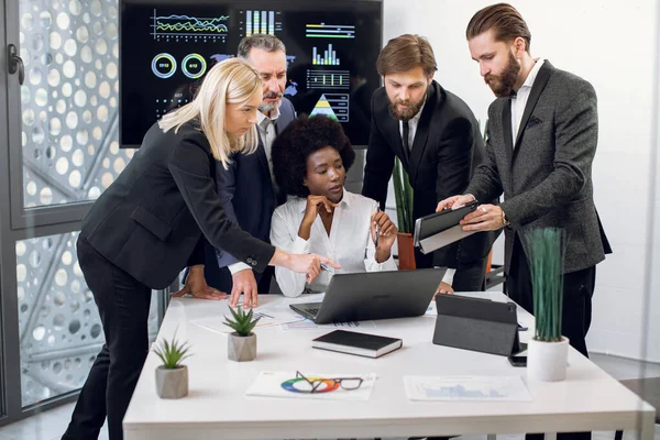 Gros plan d'hommes d'affaires multiethniques confiants avec une dirigeante africaine, travaillant ensemble au bureau, utilisant un ordinateur portable et une tablette, discutant de stratégie d'entreprise ou de nouvelle start-up. — Photo